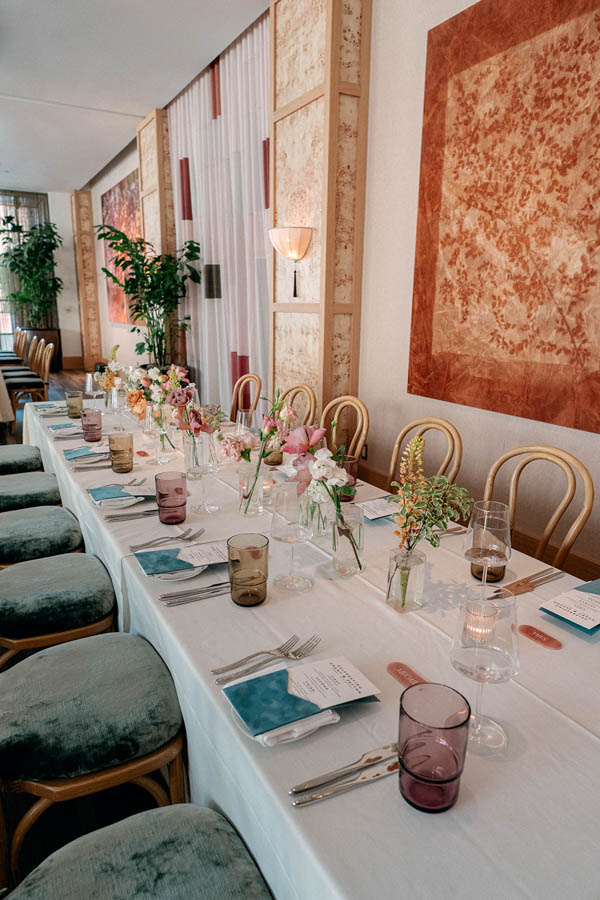 A cozy rehearsal dinner at a rustic venue, with soft lighting and floral centerpieces adorning the tables as the couple and their loved ones enjoy a casual meal, laughing and sharing stories.