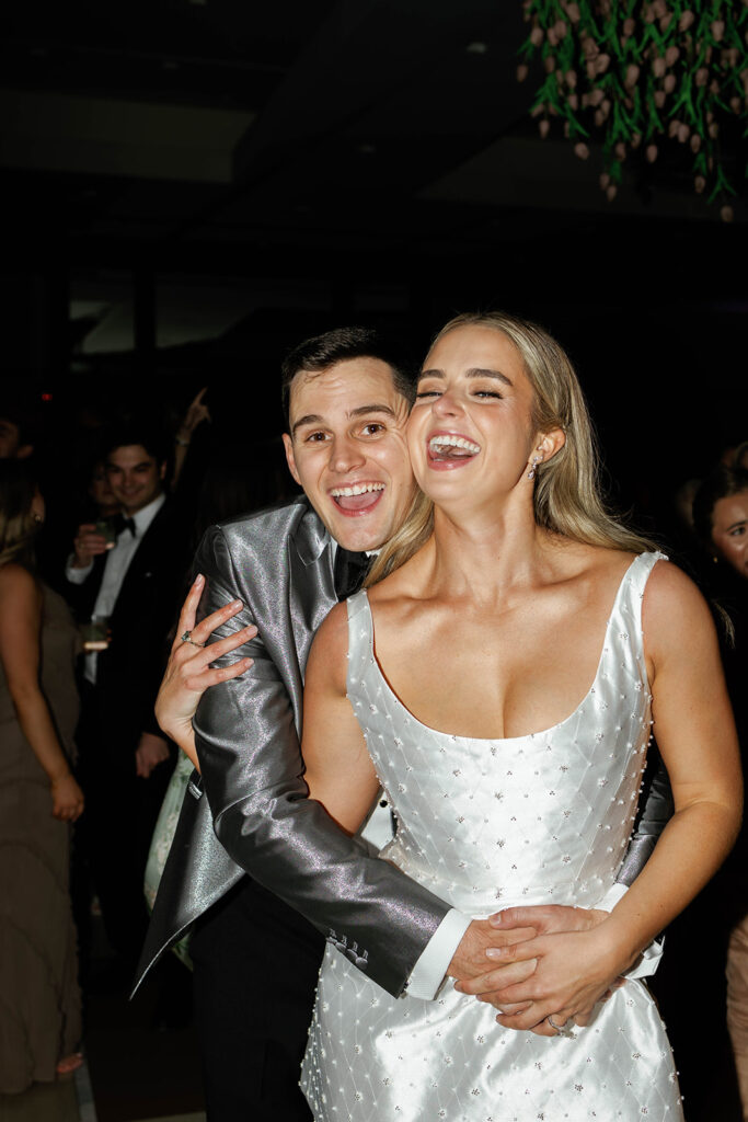 Guests laughing and chatting at the wedding reception, with a joyful atmosphere as everyone raises their glasses in a toast to the newlyweds, dancing and celebrating