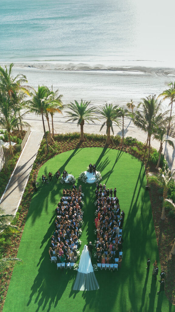 Drone view of The St. Regis Longboat Key wedding ceremony overlooking the ocean with elegant white florals and palm trees.