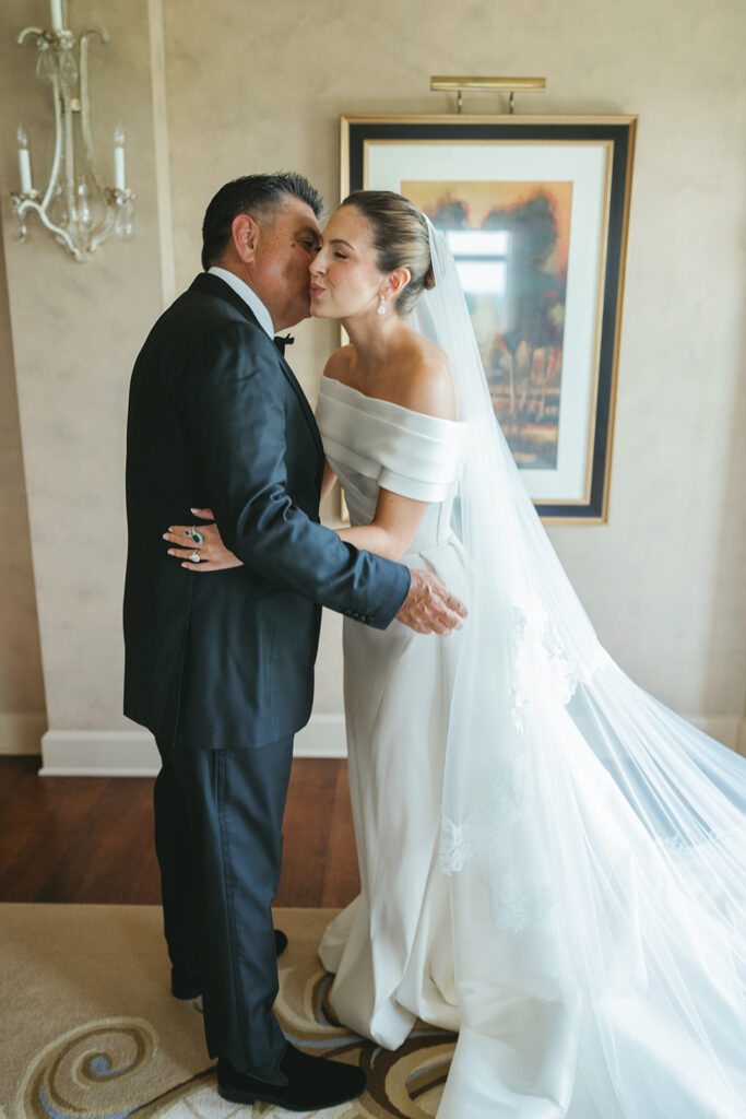 Bride getting ready for a classic Texas country club wedding wearing an off-the-shoulder gown and veil in a refined bridal suite